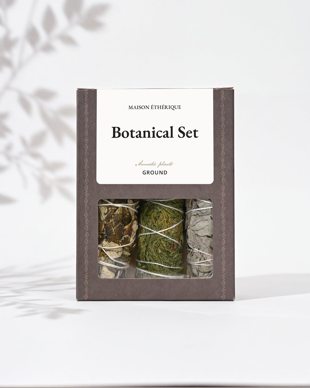 Botanical Set — Ground: grey-brown Maison Éthérique box with a window showing three bundles of white sage, cedar and yerba santa.