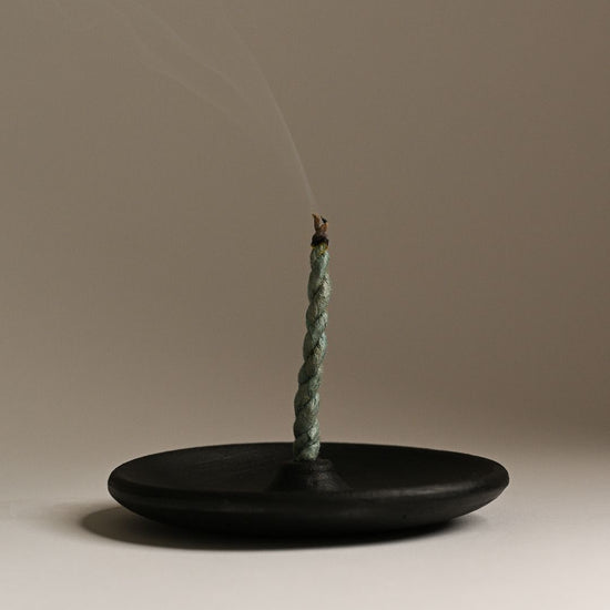 Incense stick with smoke on a clay holder