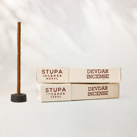 Devdar incense sticks, tube of 15: two Stupa paper boxes beside a stick standing in a small holder.