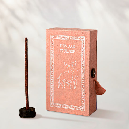 Devdar Stupa Incense Sticks, box of 40: pink handmade paper box with a deer motif beside one stick in a small holder.