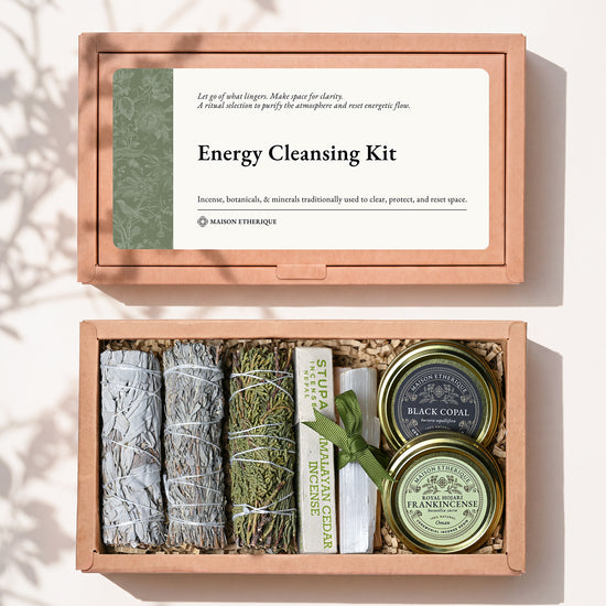 Energy Cleansing Kit: kraft box lid above the open box with three smudge sticks, Palo Santo, Himalayan Cedar incense and tins of frankincense and black copal.