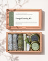Energy Cleansing Kit: kraft box lid above the open box with three smudge sticks, Palo Santo, Himalayan Cedar incense and tins of frankincense and black copal.