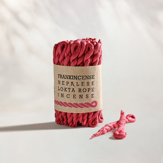 Frankincense Lokta Rope Incense Bundle: red twisted rope incense in a kraft paper band, two loose ropes beside it.