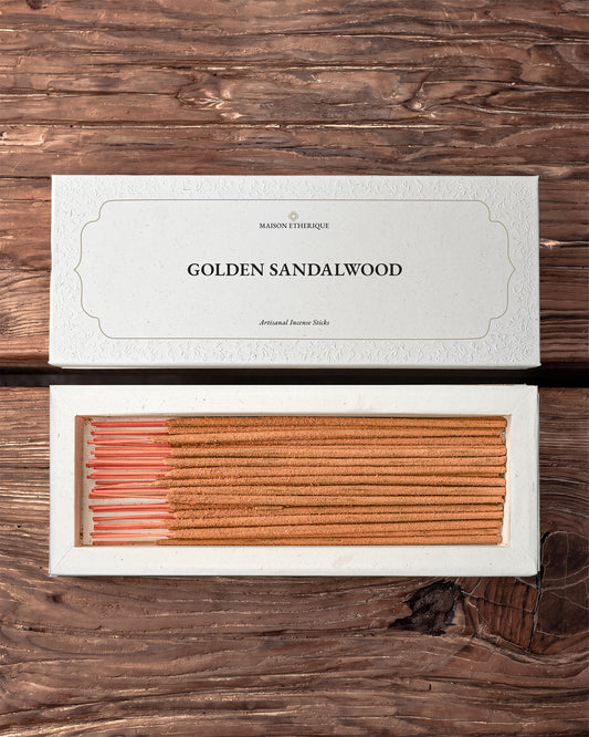 Golden Sandalwood Incense Sticks: open white Maison Éthérique box of orange-brown sticks beside its lid on dark wood.