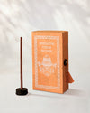 Himalayan Cedar Incense Sticks, box of 40: orange Stupa paper box with white print beside a stick standing in a small holder.