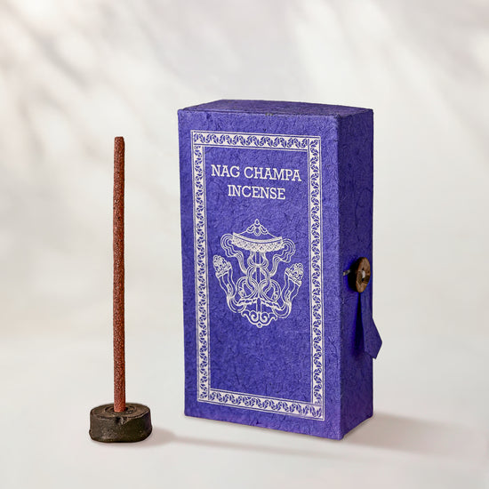 Nag Champa Incense Sticks, box of 40: purple Stupa paper box with white print beside a stick standing in a small holder.