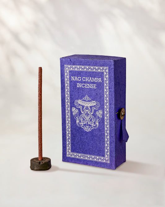 Nag Champa Incense Sticks, box of 40: purple Stupa paper box with white print beside a stick standing in a small holder.