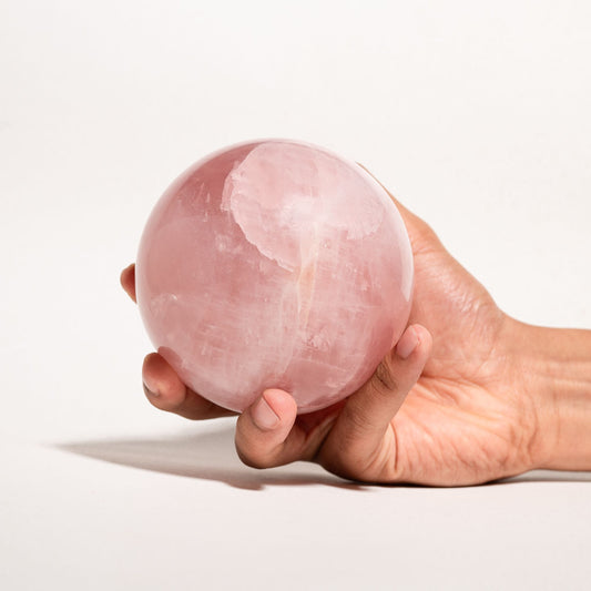 Hand holding a Rose Quartz sphere
