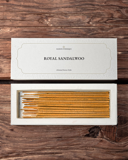 Royal Sandalwood Incense Sticks: open white Maison Éthérique box of golden-brown sticks beside its lid on dark wood.