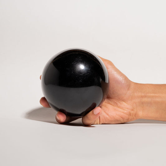 Hand holding a black Obsidian sphere 