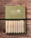 Yoga Incense Gift Box: green handmade paper box with its lid off, eight numbered paper packets of incense inside, on dark wood.