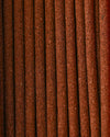 Close view of Austha Suganda incense sticks laid side by side, showing their red-brown texture.