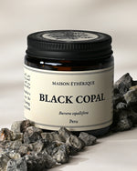 Amber glass jar of Maison Éthérique Black Copal from Peru with grey-black copal pieces arranged around its base.