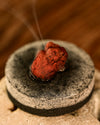 Dragon's Blood resin smouldering on a charcoal disc, a thin line of smoke rising.