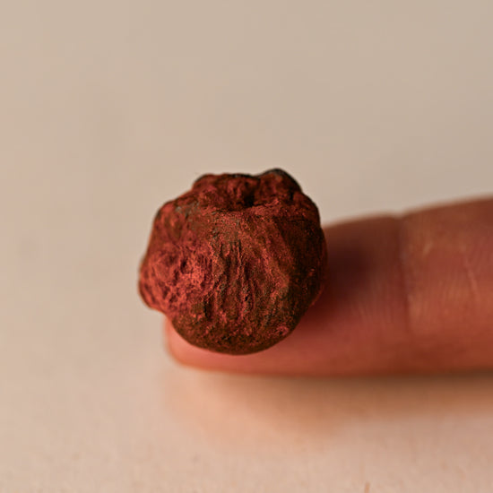 Single piece of deep red Dragon's Blood resin balanced on a fingertip.