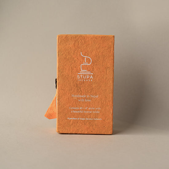 Back of an orange paper box of Stupa Himalayan Cedar incense sticks, handmade in Nepal, on a pale background.
