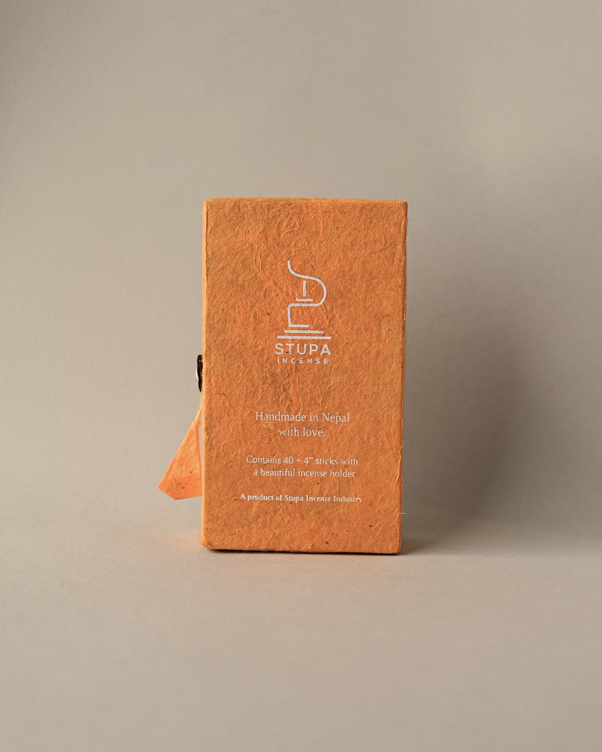 Back of an orange paper box of Stupa Himalayan Cedar incense sticks, handmade in Nepal, on a pale background.
