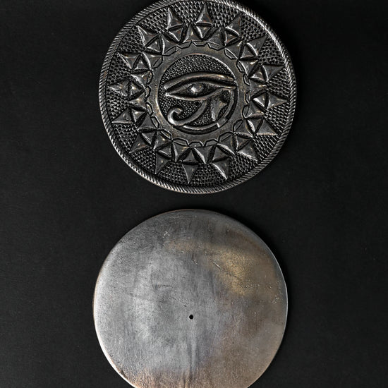 Front and plain back of the Eye of Horus metal incense holder, one above the other on a dark background.