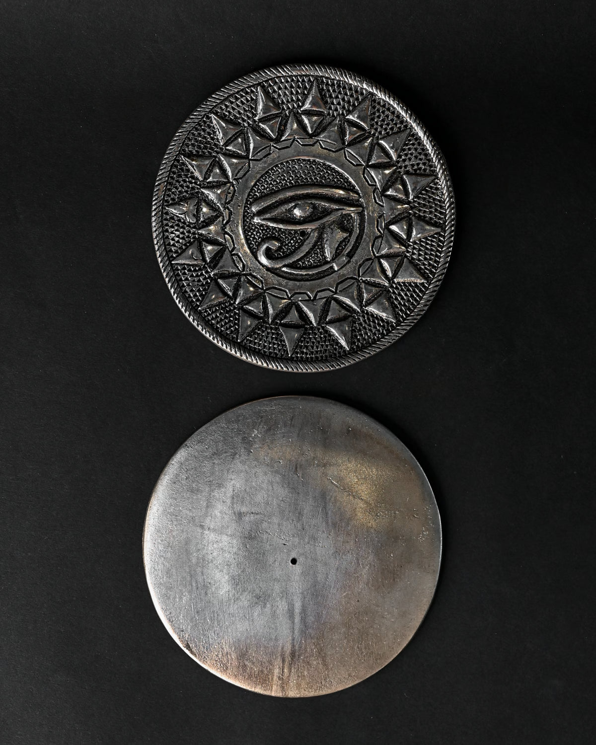 Front and plain back of the Eye of Horus metal incense holder, one above the other on a dark background.