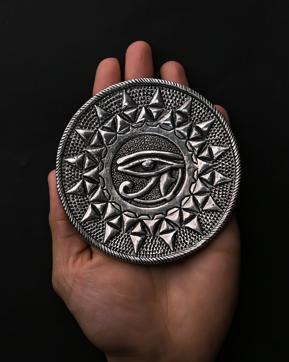 Eye of Horus metal incense holder resting on an open palm.