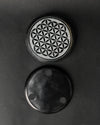 Front and underside of the round Flower of Life stone incense holder, one above the other on a dark background.