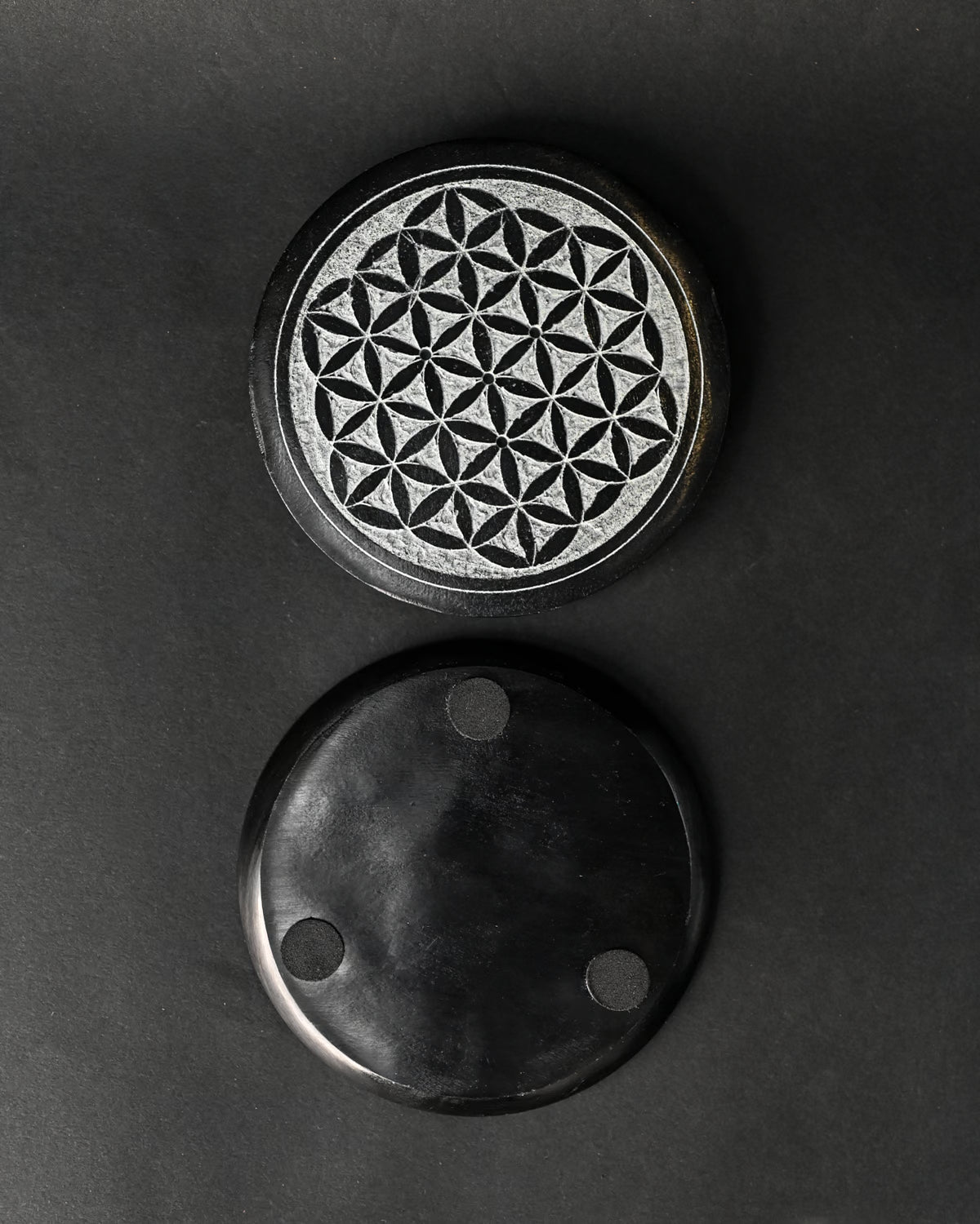 Front and underside of the round Flower of Life stone incense holder, one above the other on a dark background.