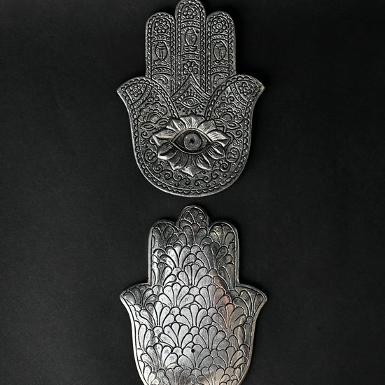 Front and back of the hand-shaped metal incense holder, one above the other on a dark background.