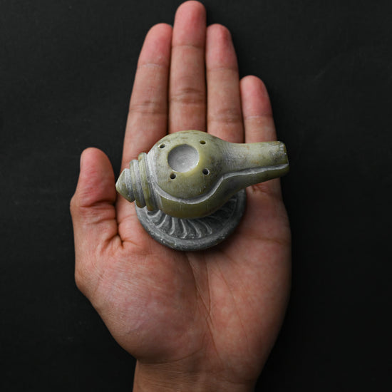 Conch-shaped Shankh stone incense holder resting on an open palm.