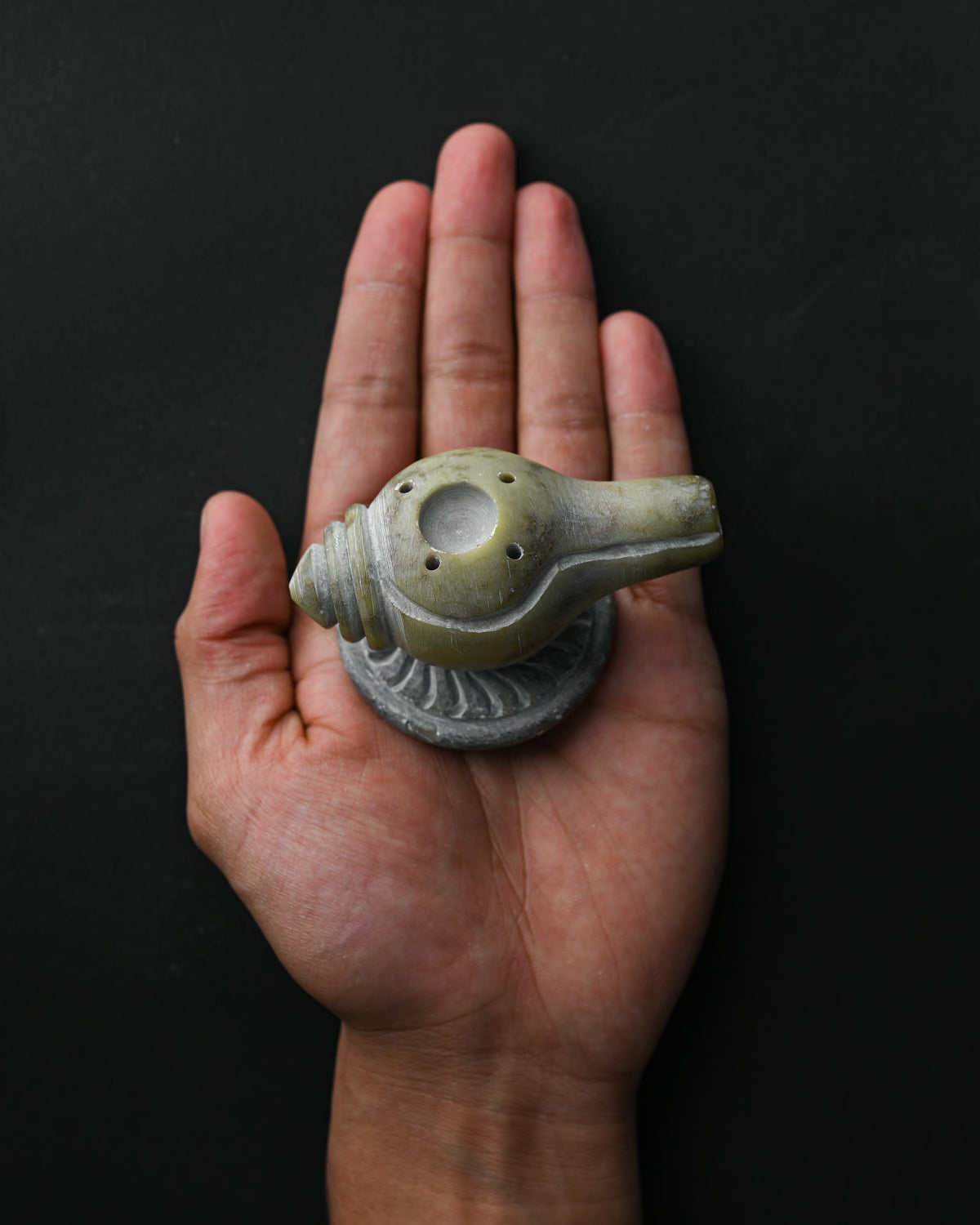 Conch-shaped Shankh stone incense holder resting on an open palm.
