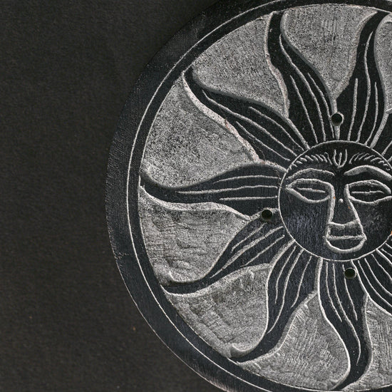 Close view of the sun face carved into the Soleil Noir stone incense holder.