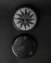 Front and underside of the Soleil Noir stone incense holder, one above the other on a dark background.