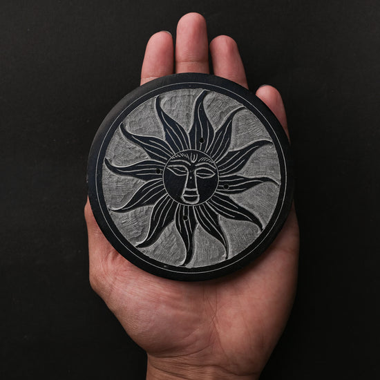 Soleil Noir carved stone incense holder resting on an open palm.