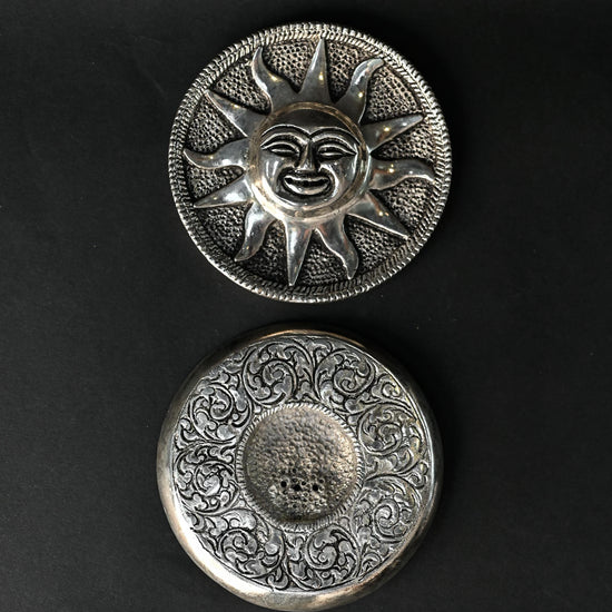 Front and back of the Surya metal incense holder, one above the other on a dark background.