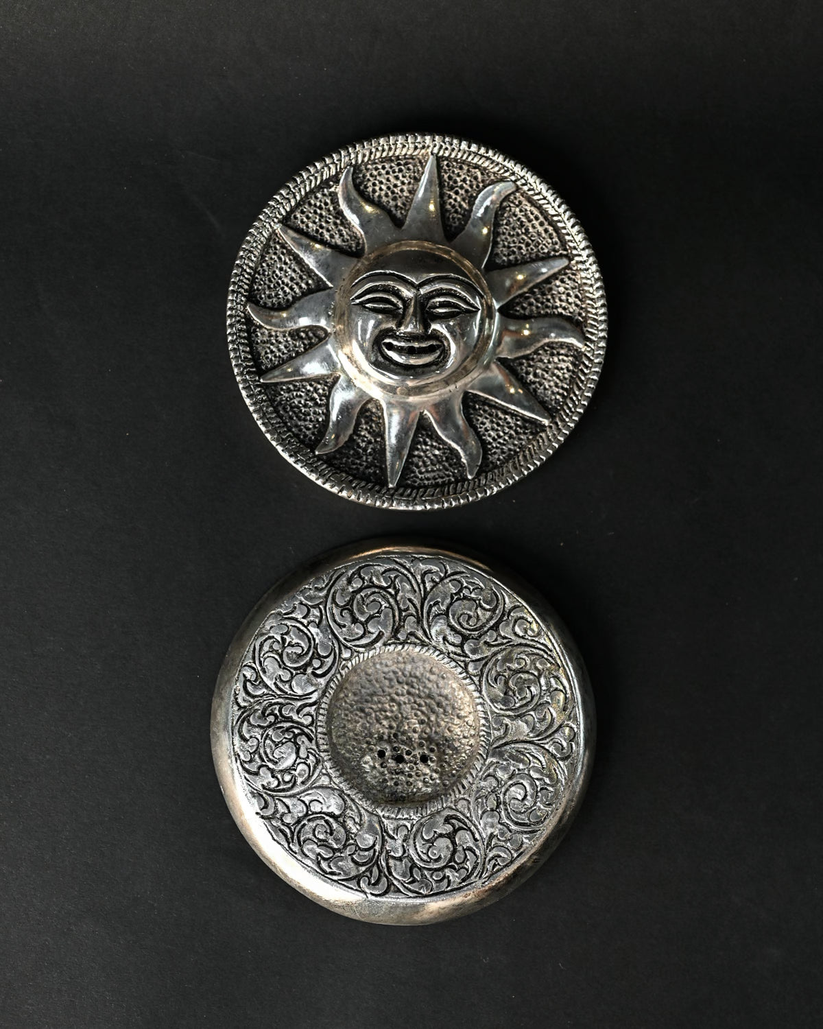 Front and back of the Surya metal incense holder, one above the other on a dark background.