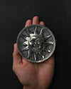 Surya sun-face metal incense holder resting on an open palm.