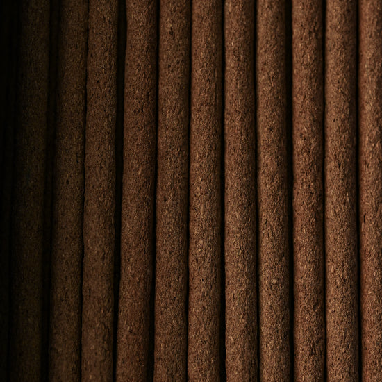 Close view of Nag Champa incense sticks laid side by side, showing their dark brown texture.