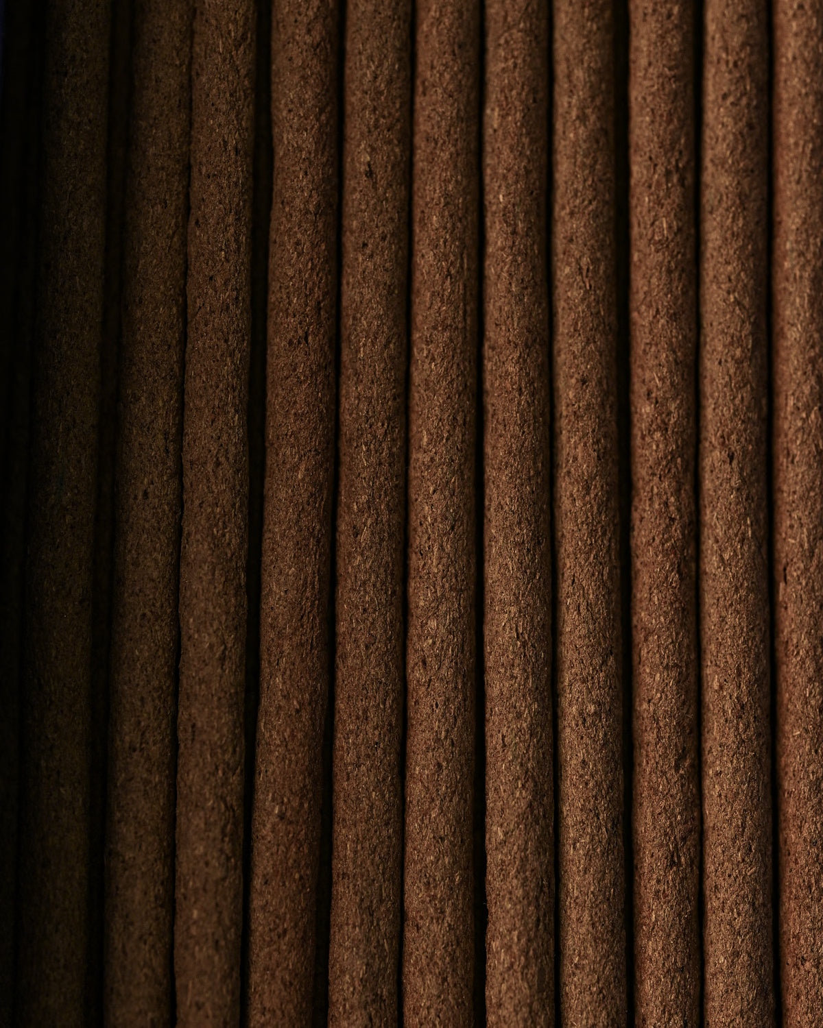 Close view of Nag Champa incense sticks laid side by side, showing their dark brown texture.