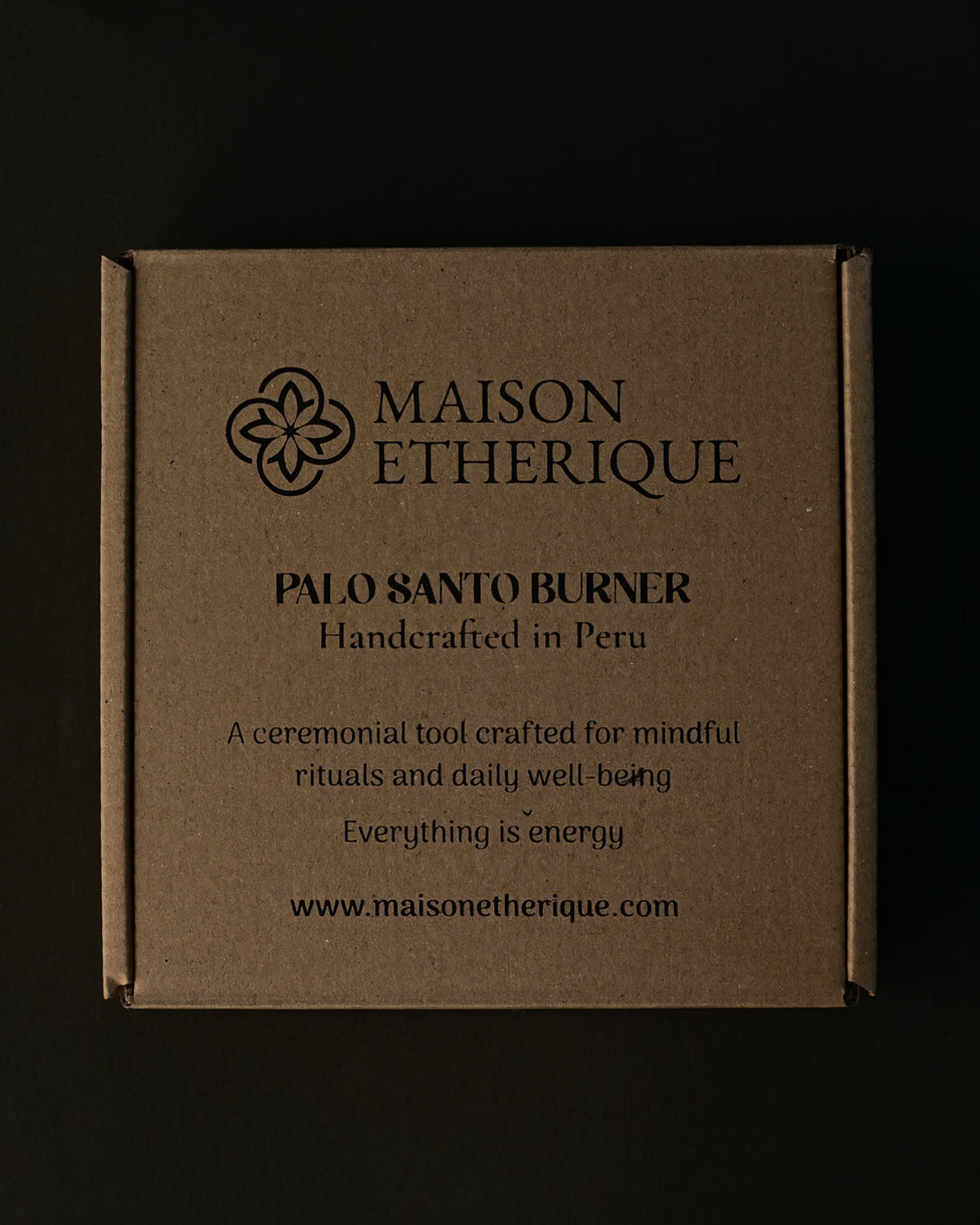 Kraft card box for the Maison Éthérique Palo Santo burner, handcrafted in Peru, on a dark background.