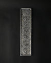 7 Chakra incense stick holder in silver-toned metal, embossed with seven symbols, seen from above on a dark background.