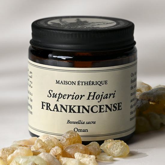 Amber glass jar of Maison Éthérique Superior Hojari Frankincense from Oman with pale frankincense tears in the foreground.
