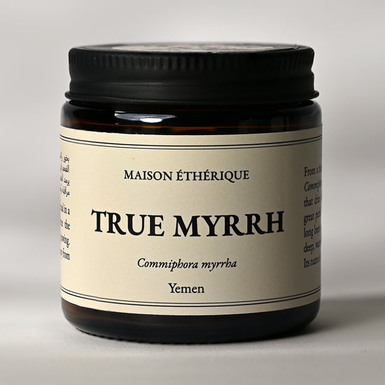 Amber glass jar of Maison Éthérique True Myrrh (Commiphora myrrha) from Yemen, black lid, on a pale background.