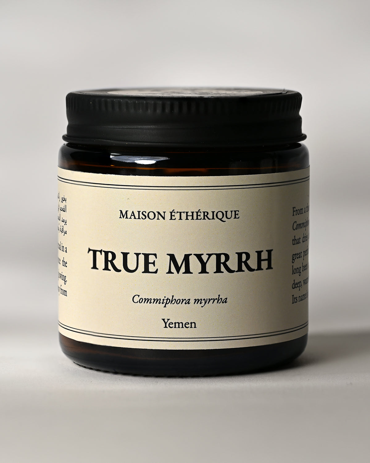 Amber glass jar of Maison Éthérique True Myrrh (Commiphora myrrha) from Yemen, black lid, on a pale background.