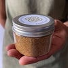 A hand holding a jar of Palo Santo Powder by Maison Etherique