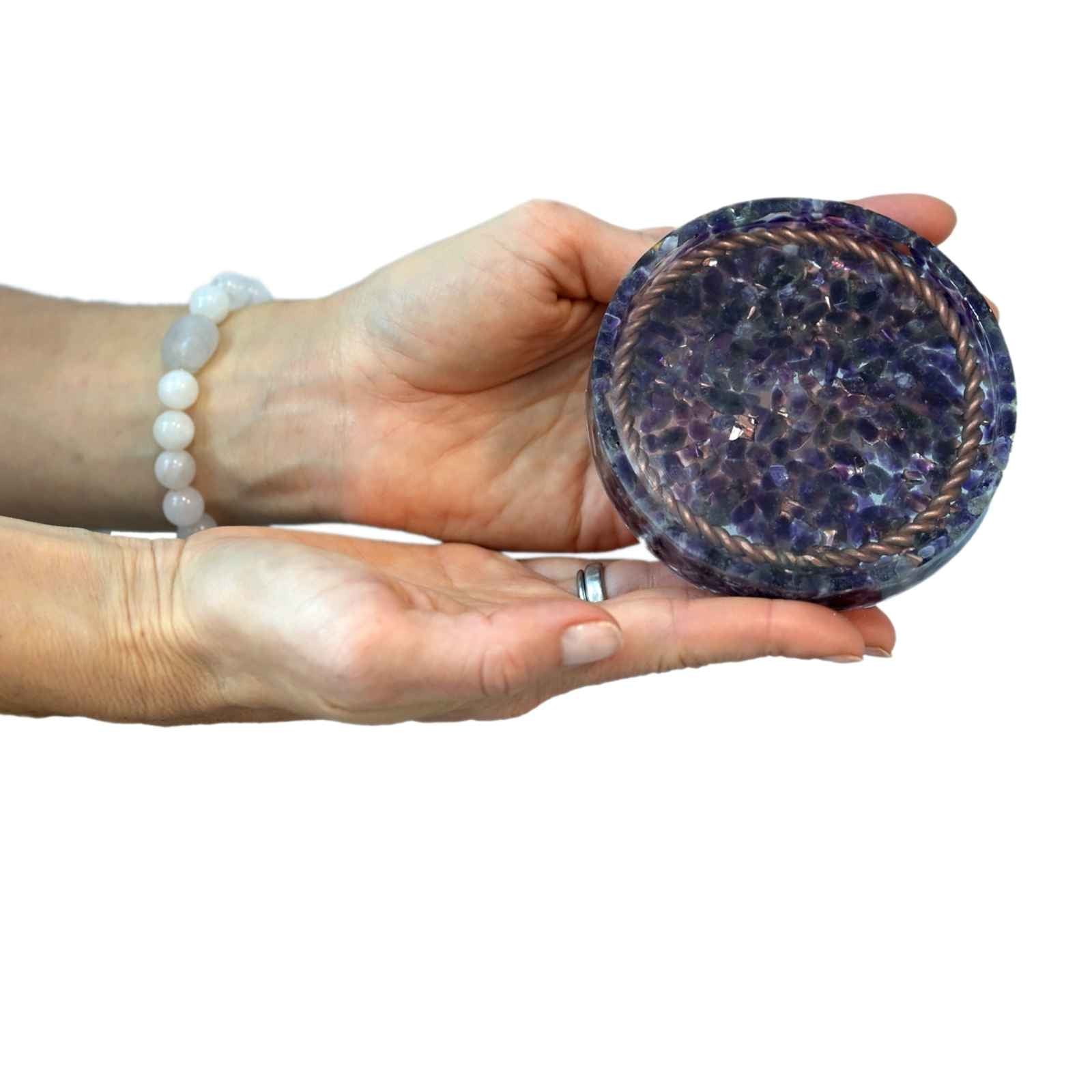 A close up of a person holding an Orgone Coasters