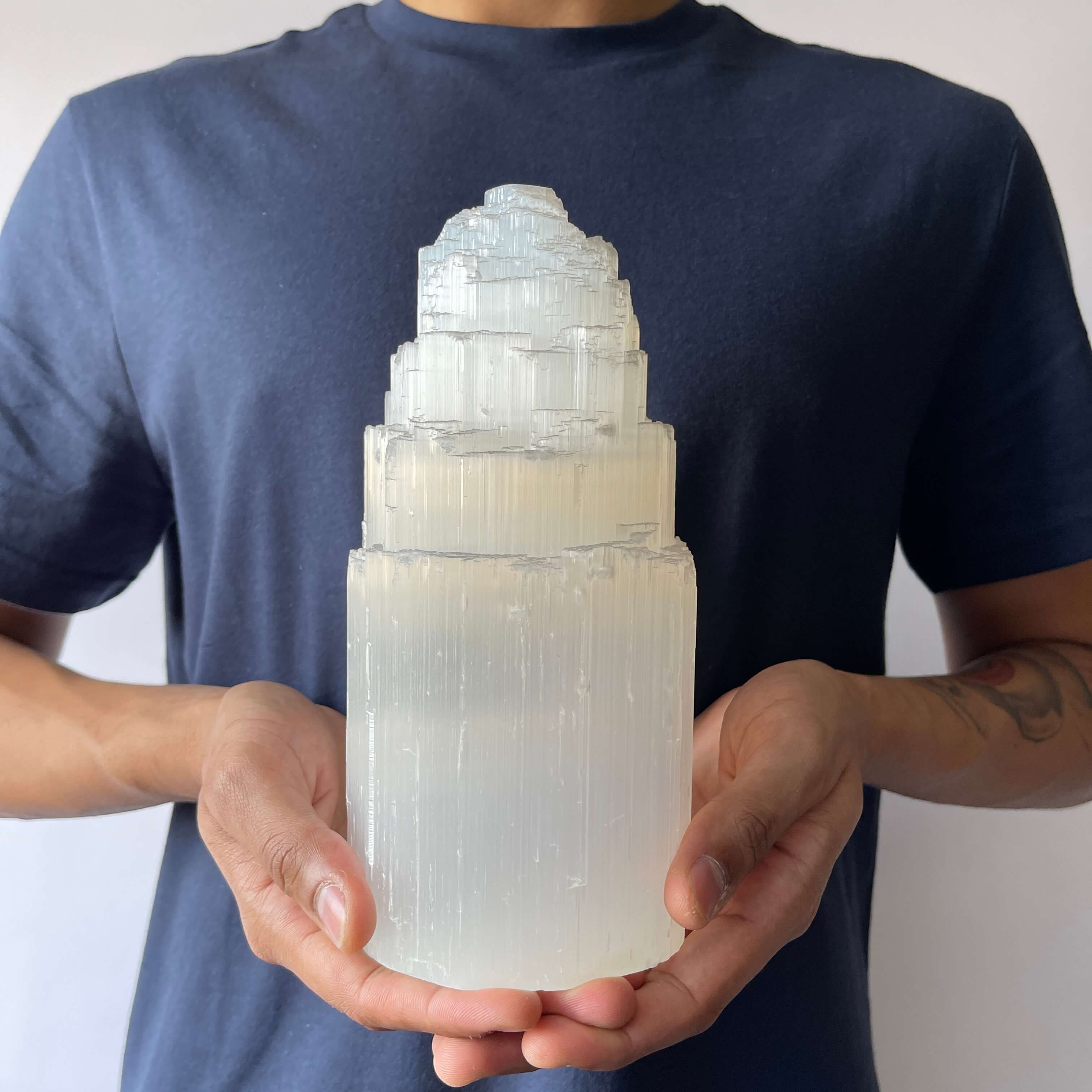 A man holding A Selenite Crystal Tower - 20cm 