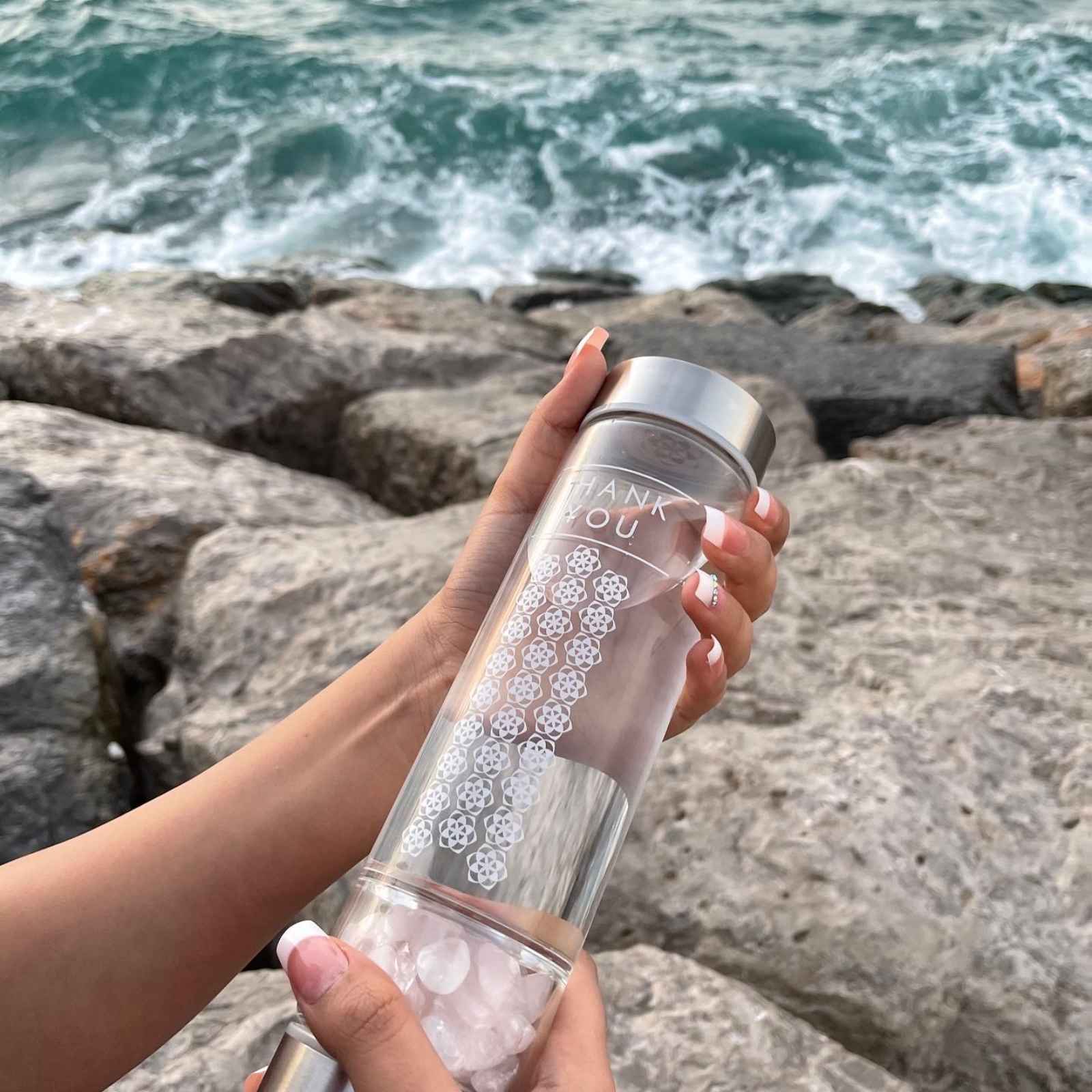 A woman holding a A Crystal Water Bottle with Tumbled Rose Quartz